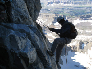 Dave Angus descends a mountain with ropes, helmet, and carabiner