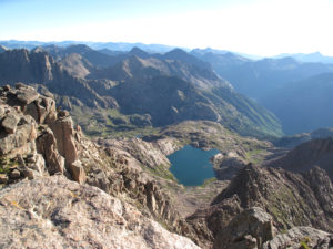 View from up high looking over mountain ranges and an alpine lake