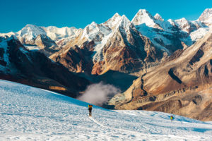 A mountaineer treks across snow toward epic peaks